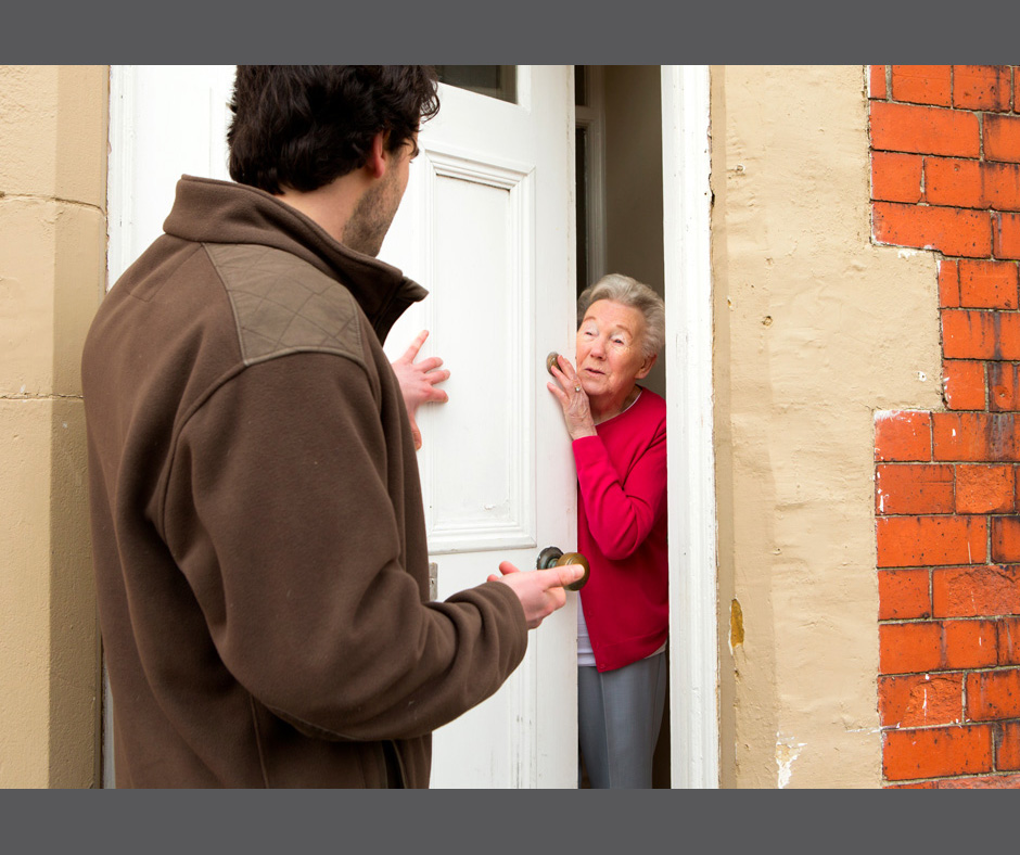 Bild zeigt einen Mann von hinten der mit einer Frau spricht. Dabei drückt er mit der Hand die Haustür auf. Die Frau steht in der Tür und hält vorsichtig ihre Haustür geöffnet, betrachtet ihn aber mit kritischem Blick. Es soll vor unseriösen Haustürgeschäften warnen.