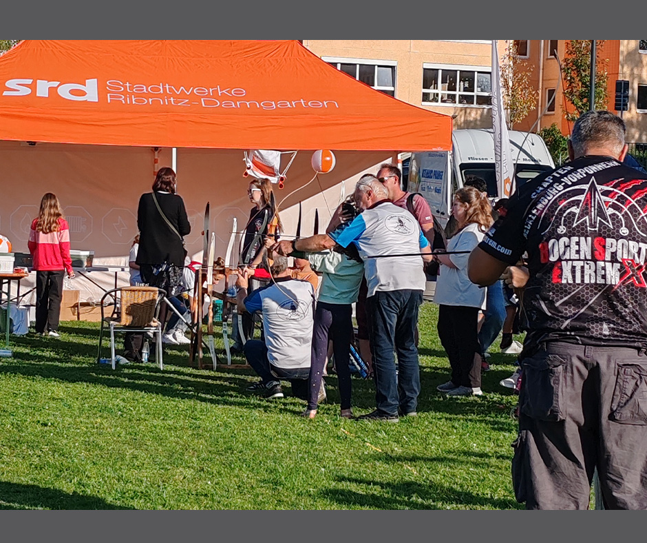 Bild zeigt die drei Schützen, die gerade den Teilnehmenden des Familienfestes das richtige Bogenschießen beibringen.